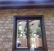 Окна и дверные проёмы отделаны коричневой околооконной планкой